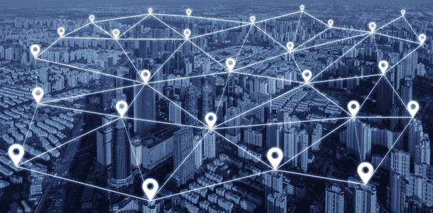 Aerial view of a city overlaid with a digital network. White location pins and connecting lines form a mesh, depicting connectivity and urban technology.