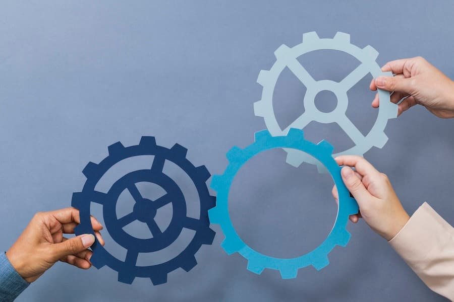 Multiple hands holding interlocking gears, symbolizing the configuration and integration of system components.