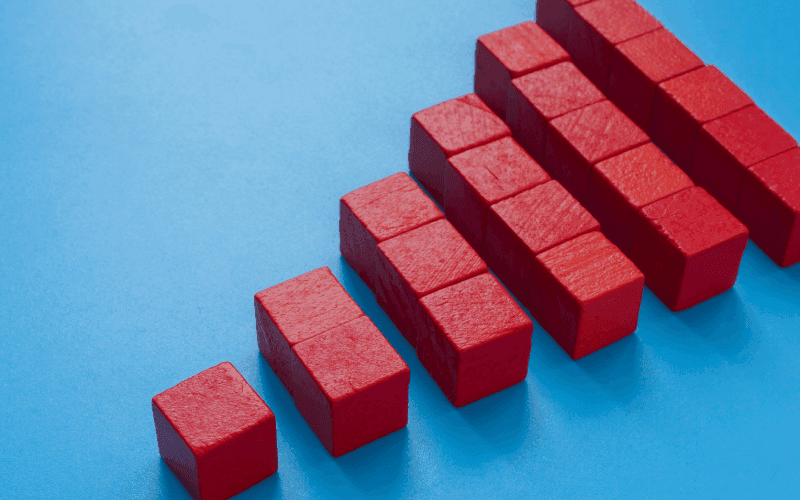 Red blocks arranged in ascending order on a blue background, forming a bar graph. The image conveys growth or progress.