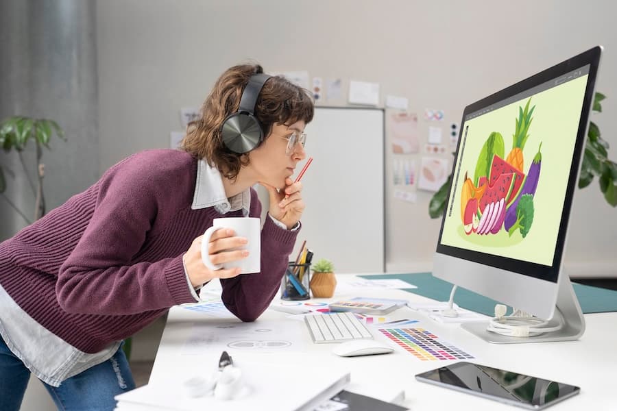 A designer analyzing colorful graphics on a computer monitor, representing the design phase of a project workflow.