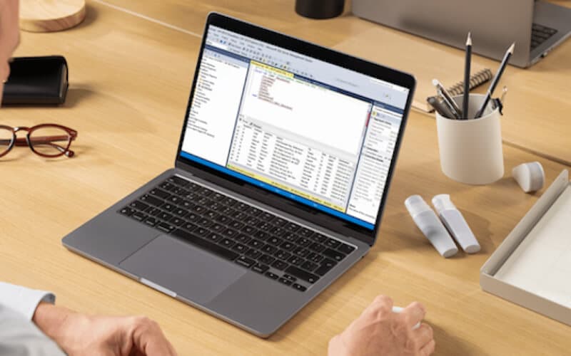 A workspace setup with a laptop displaying a business dashboard, highlighting enterprise application hosting and database management.