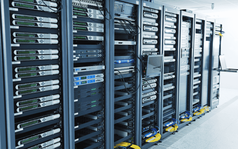 A row of server racks filled with computer equipment and cables in a data center. The room is well-lit and orderly, conveying a high-tech atmosphere.