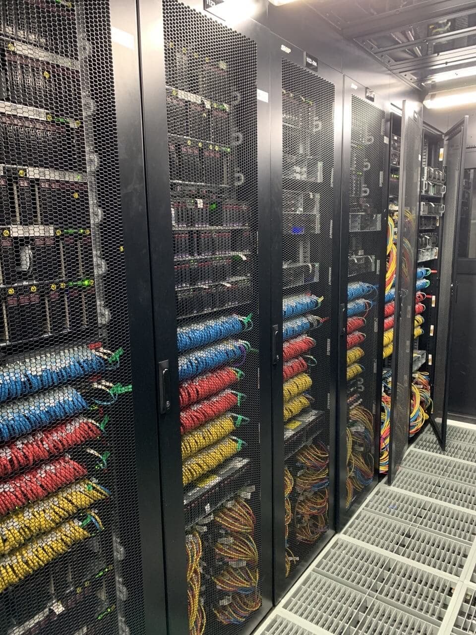 Close-up view of server racks with organized color-coded network cabling in blue, red, and yellow for efficient routing and management
