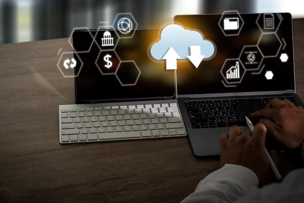 Hands typing on a laptop with a digital cloud icon and data symbols, symbolizing cloud computing.