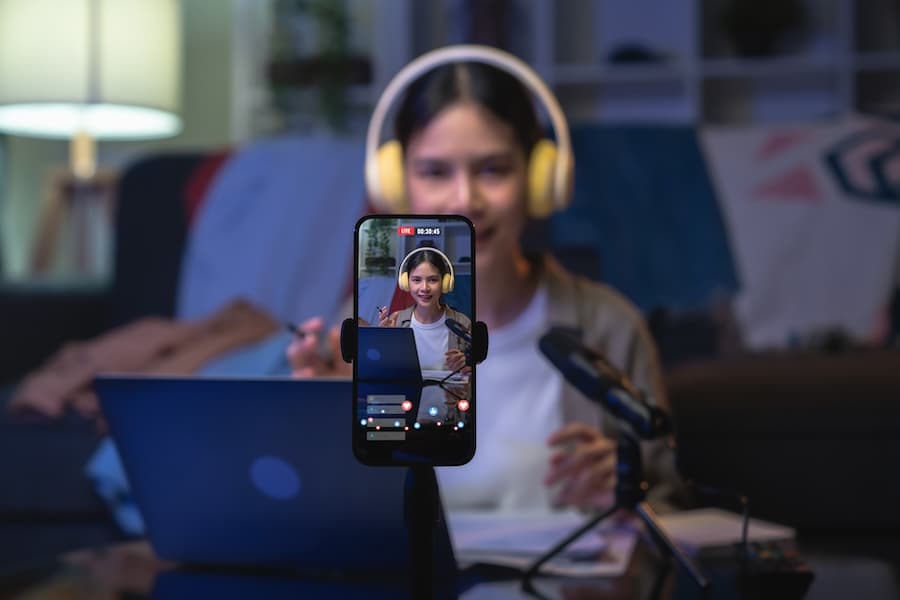 A content creator wearing headphones and holding a smartphone while streaming live, representing high-quality video streaming services.