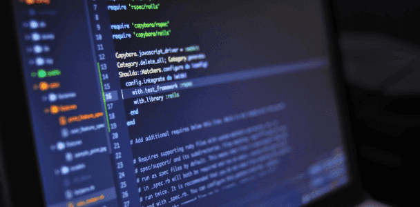 Close-up of computer screen displaying code in a text editor. Lines of colorful code indicate a programming environment, conveying a focused, tech-savvy mood.
