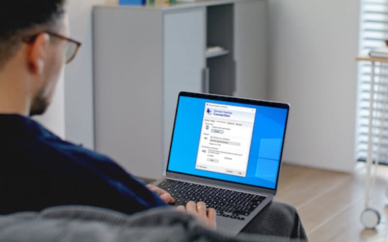 A person using a laptop with a remote desktop interface, representing cloud-based Windows workstations for remote access to enterprise software.