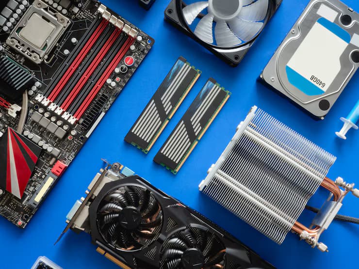 Computer components on a blue background, including a motherboard, RAM sticks, hard drive, cooling fan, and heat sink.