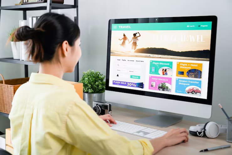 A woman in a yellow shirt browses travel deals on a desktop.