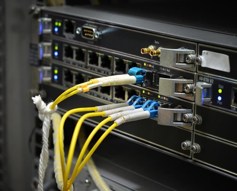 A close-up photo of network server equipment with multiple yellow fiber optic cables connected to ports.