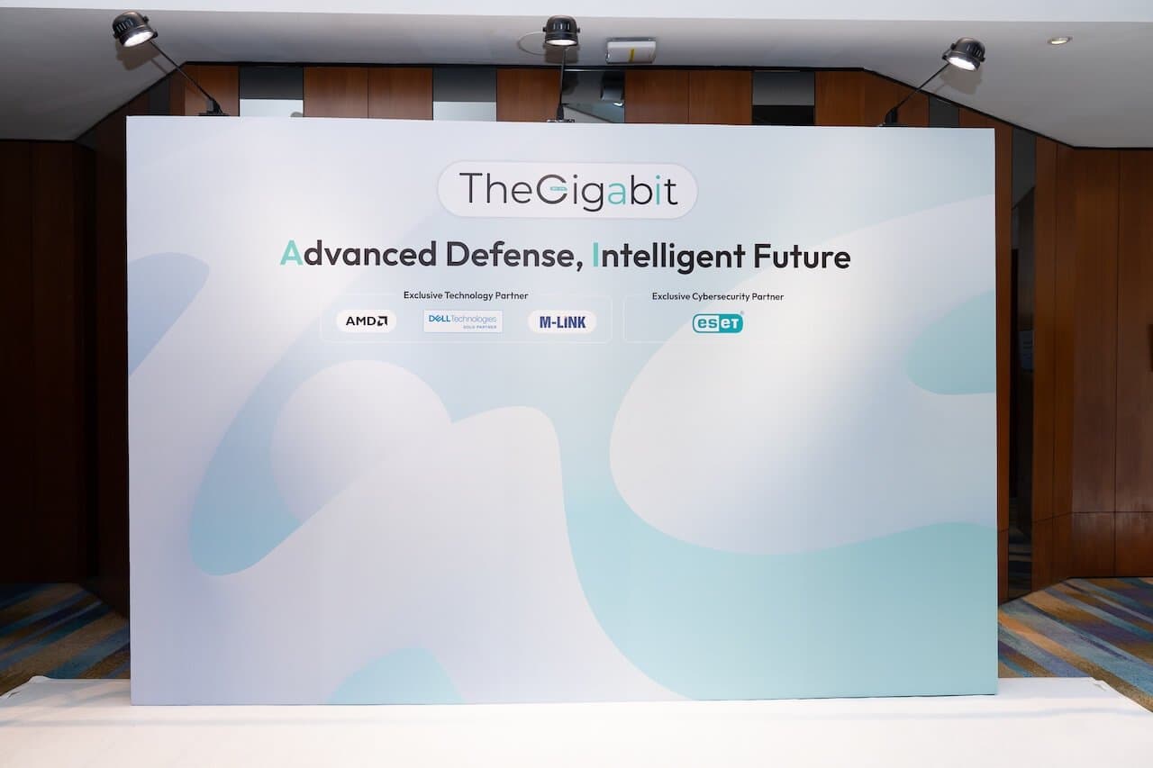 Backdrop displaying 'The Gigabit' logo with the slogan 'Advanced Defense, Intelligent Future.' Includes logos for AMD, Dell, M-Link, and ESET. Modern setting. Backdrop displaying 'The Gigabit' logo with the slogan 'Advanced Defense, Intelligent Future.' Includes logos for AMD, Dell, M-Link, and ESET. Modern setting.
